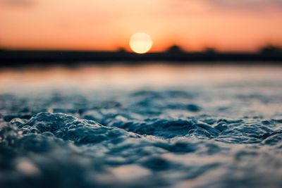 Surface level of sea against sunset sky