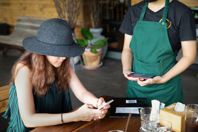 Midsection of woman using mobile phone while sitting on table