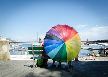 Multi colored umbrella by sea against sky
