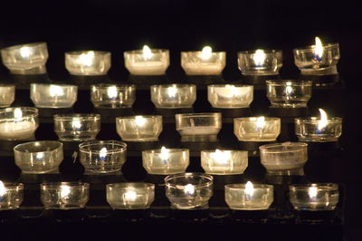 Close-up of illuminated tea light candles in darkroom