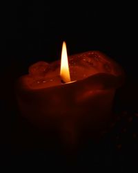 Close-up of illuminated candle against black background