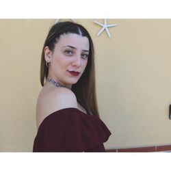 Portrait of smiling young woman against wall