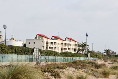 Built structure on beach by houses against sky