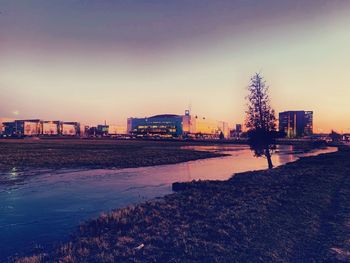 Scenic view of river by buildings against sky at dusk