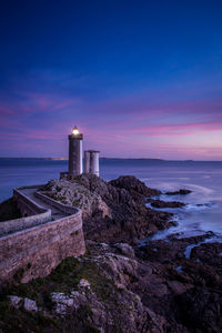 Lighthouse by sea against sky during sunset