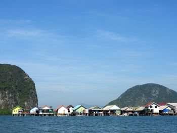 Buildings by sea against blue sky