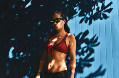 Woman wearing bikini top standing by wall