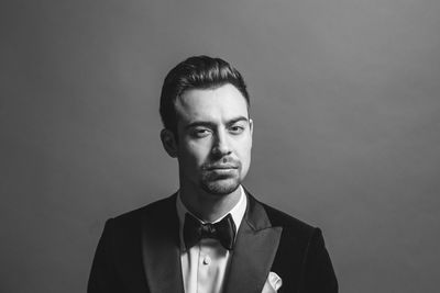 Portrait of young man standing against gray background