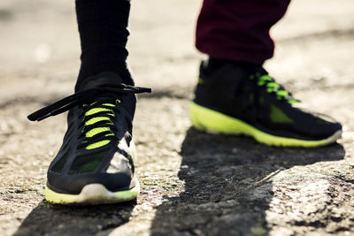 Low section of man wearing black sports shoes standing on rock