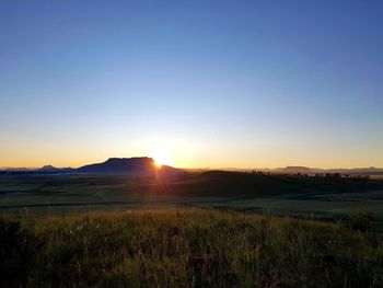 Scenic view of field against clear sky during sunset