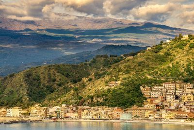 Scenic view of townscape by mountains against sky