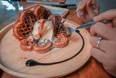 Close-up of hand holding ice cream on table