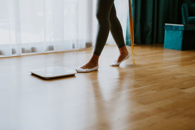 Low section of woman standing on floor at home