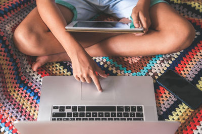 Low section of boy using digital tablet and laptop at home