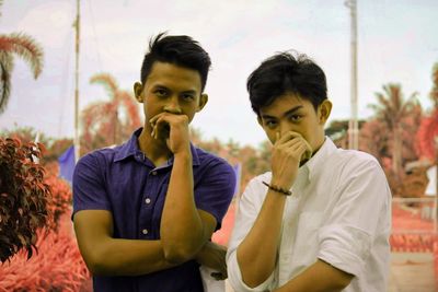 Portrait of young friends standing against sky