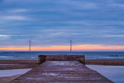 Pier over sea against sky during sunset