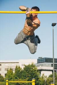 Full length of shirtless man jumping against sky