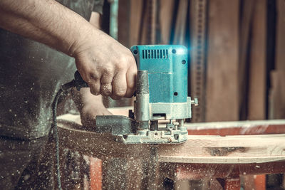 Midsection of carpenter cutting wood in workshop