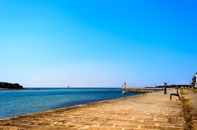 Scenic view of beach against clear blue sky