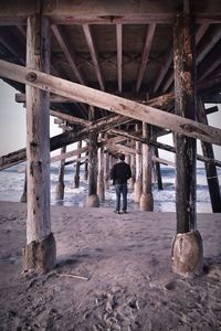 Rear view of man standing on pier at beach