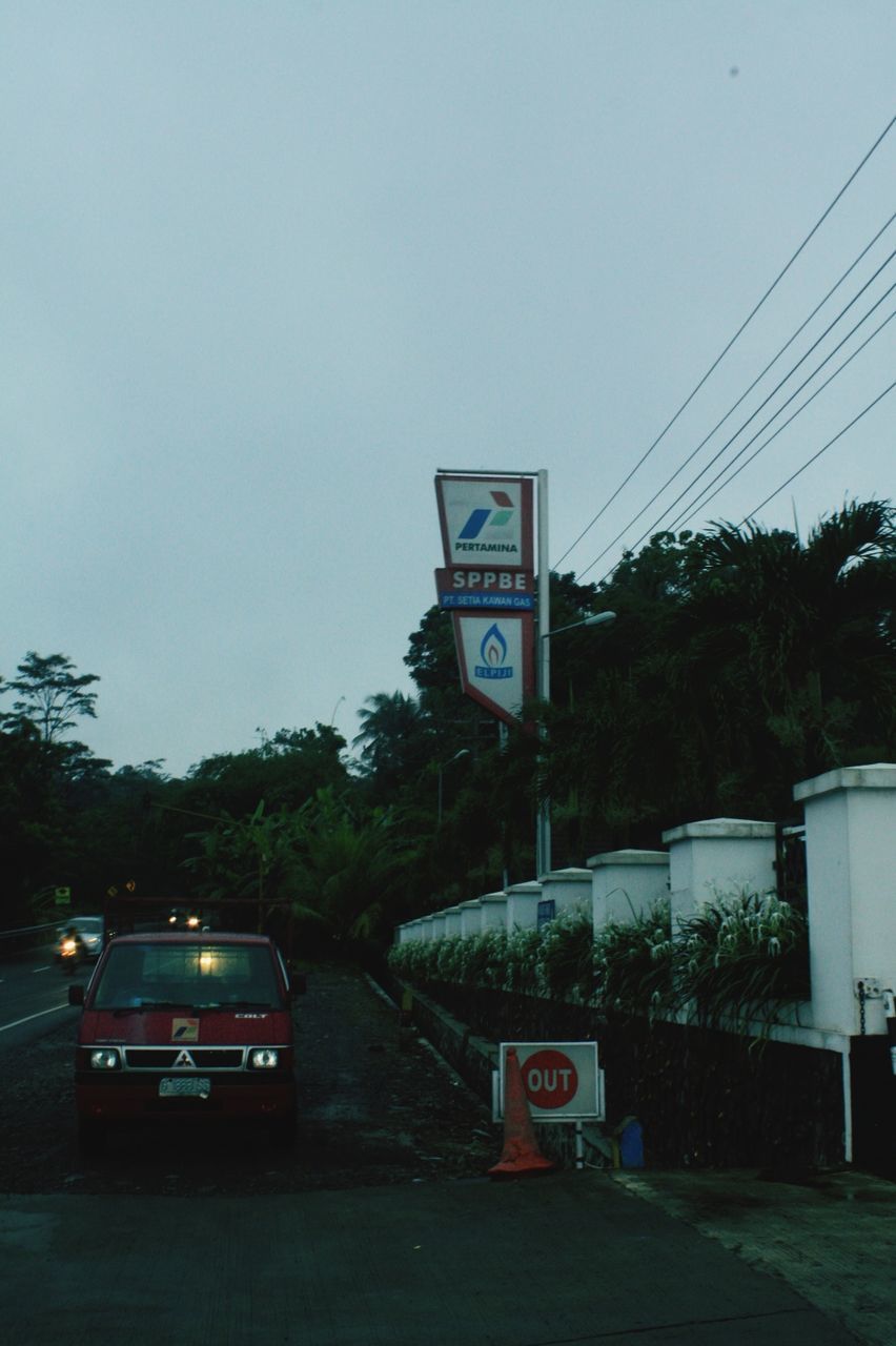 text, communication, transportation, western script, clear sky, tree, road sign, information sign, sign, road, guidance, warning sign, land vehicle, street, capital letter, car, information, mode of transport, non-western script, architecture