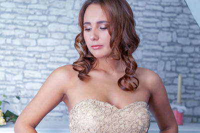 Portrait of a young woman standing against wall