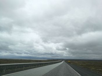 Country road against cloudy sky