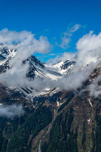 Scenic view of snowcapped mountains against blue sky