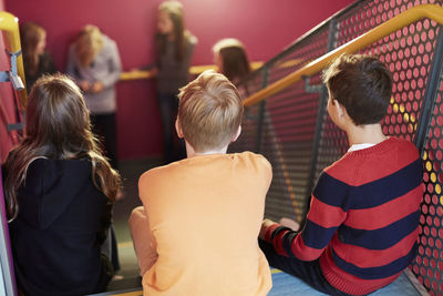 Rear view of junior high students sitting on school staircase