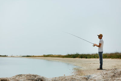 Rear view of man walking at beach against clear sky