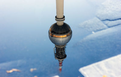 High angle view of fernsehturm against sky reflecting in puddle