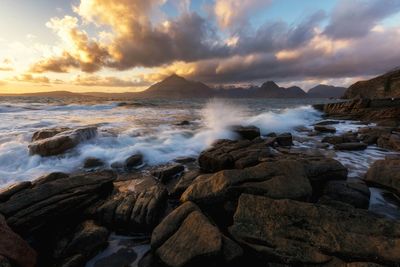 Rocks in sea at sunset