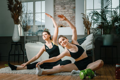 Positive athletic women with neatly tied hair and tight sportswear stretching 