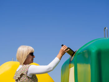 Rear view of woman holding umbrella against blue sky