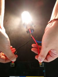 Close-up of hands holding illuminated lighting equipment