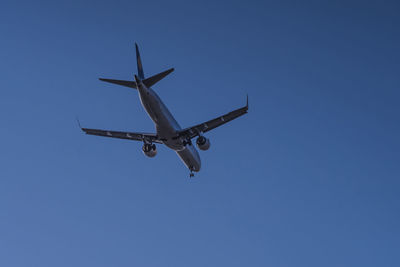 Low angle view of airplane against clear blue sky