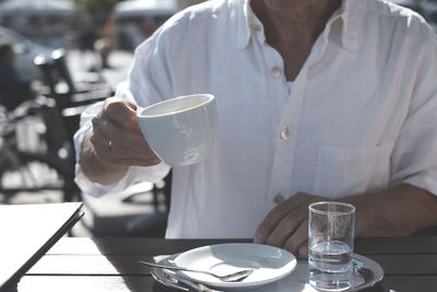 Midsection of man holding drink on table