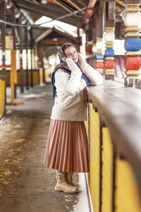 A slavic woman in a national colored scarf, a fur coat and  mittens on the porch of a wooden house