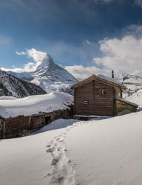 Snow covered old chalets and mountains against sky