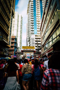 Rear view of people walking on street amidst buildings in city