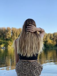 Rear view of woman looking at lake against clear sky