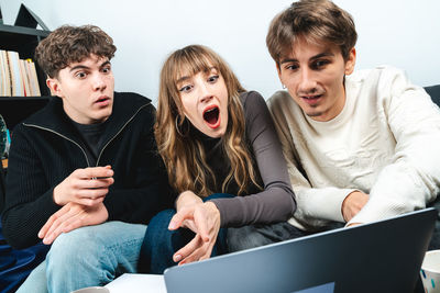 Portrait of smiling friends using mobile phone at home