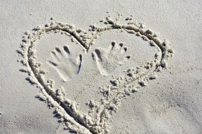 Heart in the sand with hand prints on the beach