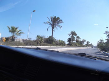 Cars on road against clear sky seen through car windshield