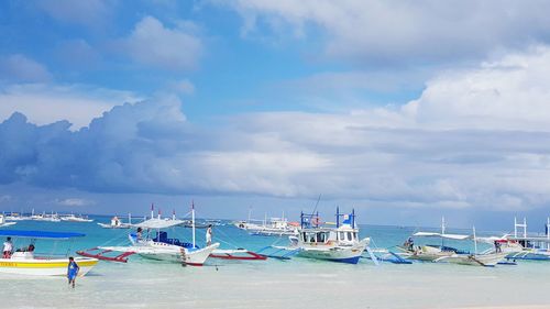 Boats sailing in sea against cloudy sky