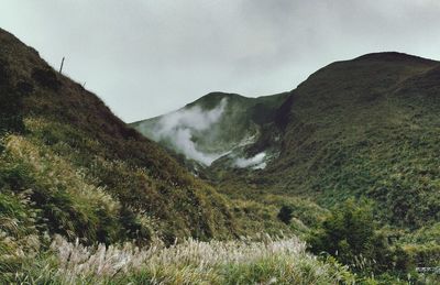 Low angle view of grassy mountains against sky