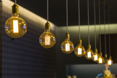 Low angle view of illuminated light bulbs hanging from ceiling