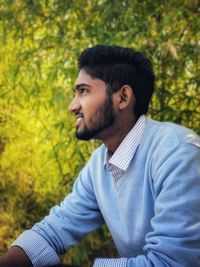 Young man looking away while standing outdoors