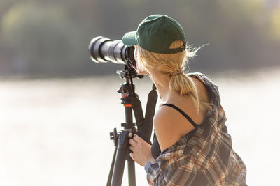 Side view of young woman holding camera