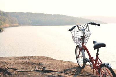 Bicycle by water against sky